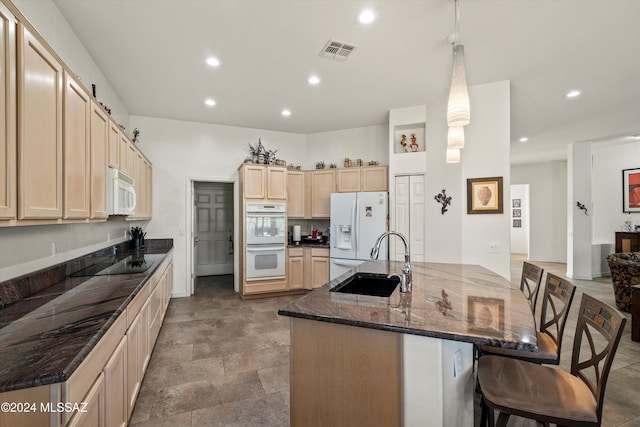 kitchen with sink, a barn door, decorative light fixtures, white appliances, and a breakfast bar