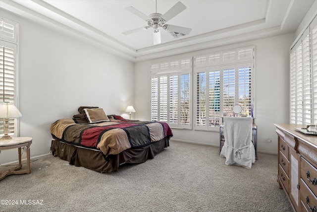 carpeted bedroom with a tray ceiling and ceiling fan