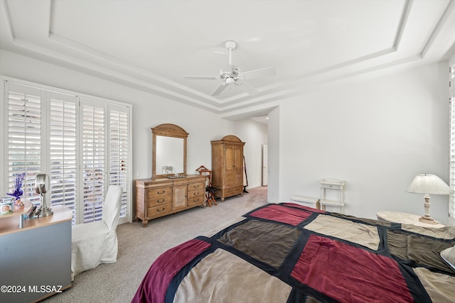 carpeted bedroom with ceiling fan and a tray ceiling