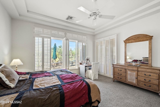 carpeted bedroom featuring a tray ceiling and ceiling fan