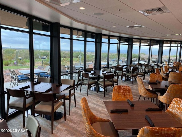 dining area with wood-type flooring, floor to ceiling windows, and a high ceiling