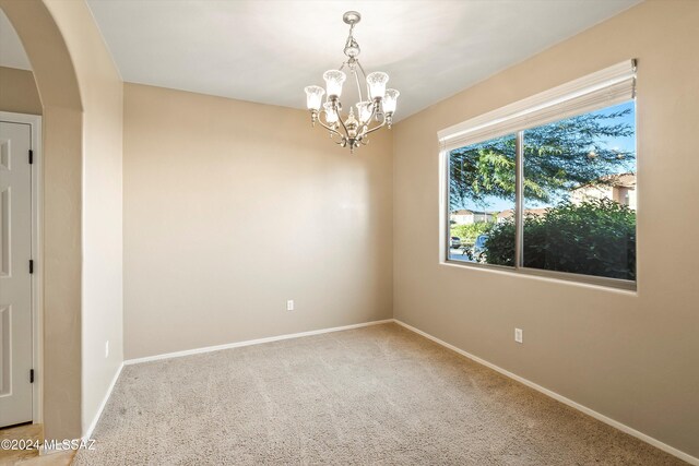 unfurnished room featuring a chandelier and light colored carpet