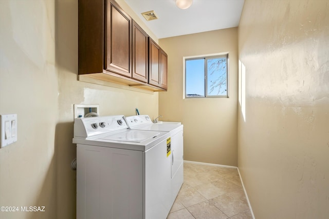 laundry room with light tile patterned flooring, cabinets, and washing machine and dryer