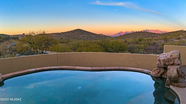 pool at dusk featuring a mountain view