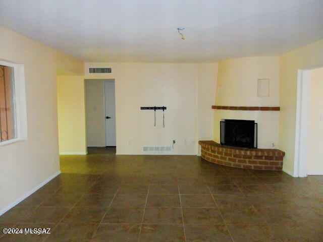 unfurnished living room with a fireplace and dark tile patterned flooring