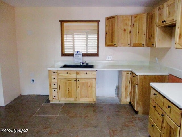 kitchen with light brown cabinets, dark tile patterned floors, and sink