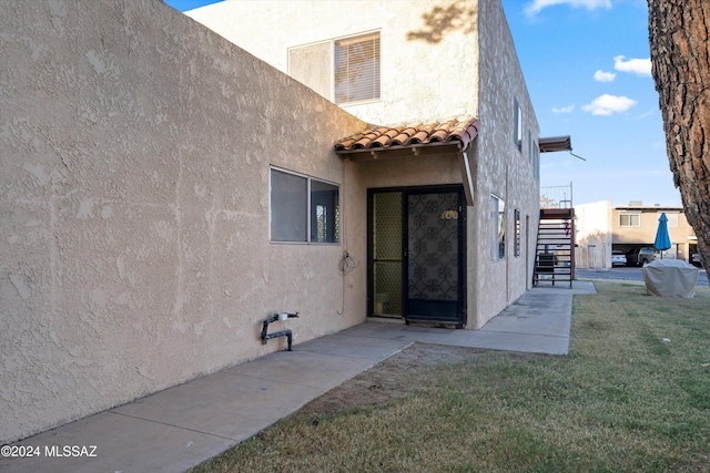 view of exterior entry featuring a lawn