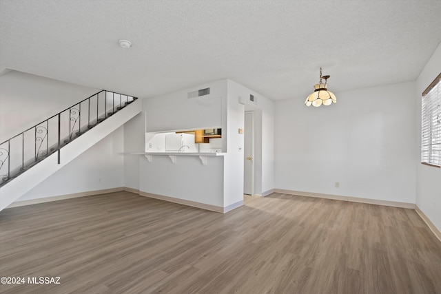 unfurnished living room with a textured ceiling and light hardwood / wood-style flooring