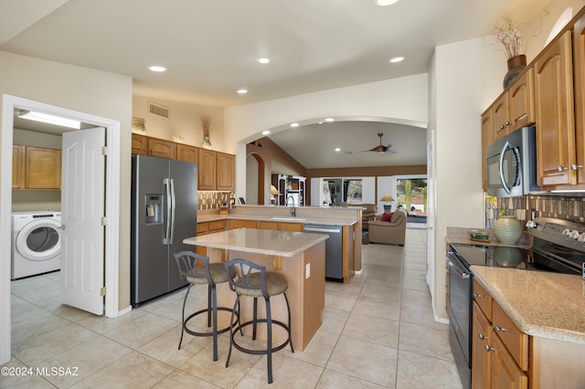 kitchen featuring sink, a center island, stainless steel appliances, kitchen peninsula, and washer / dryer