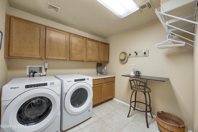 laundry room with washer and dryer, cabinets, and light tile patterned floors