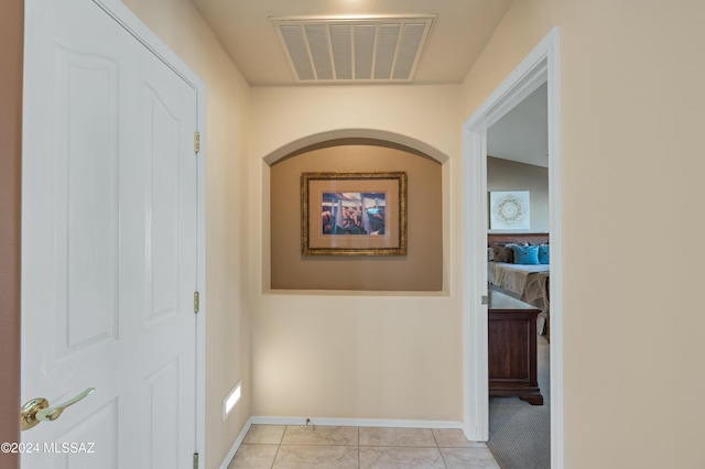 corridor featuring lofted ceiling and light tile patterned floors