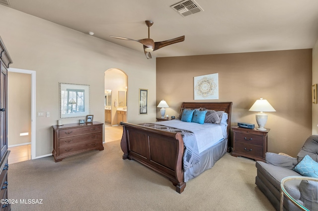 bedroom with ensuite bathroom, ceiling fan, light carpet, and vaulted ceiling