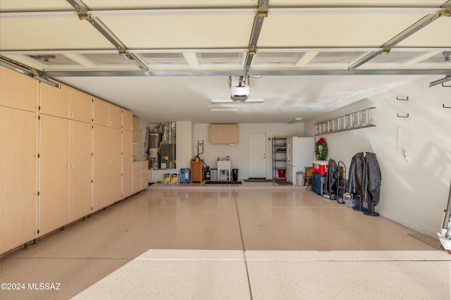 garage featuring white fridge, gas water heater, and a garage door opener