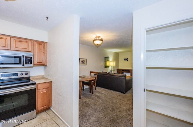 kitchen with light carpet, appliances with stainless steel finishes, and a textured ceiling