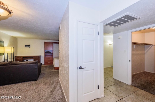 hallway featuring a textured ceiling and light carpet