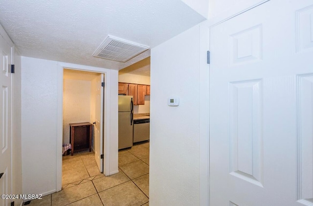 corridor with a textured ceiling and light tile patterned flooring