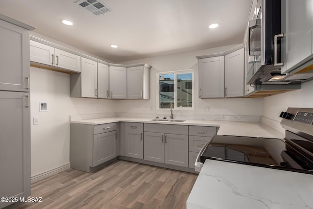 kitchen featuring gray cabinets, stainless steel appliances, a sink, and visible vents