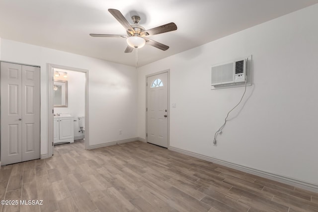 entrance foyer with light wood-type flooring, a ceiling fan, baseboards, and a wall unit AC