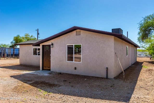 rear view of house featuring central AC and stucco siding