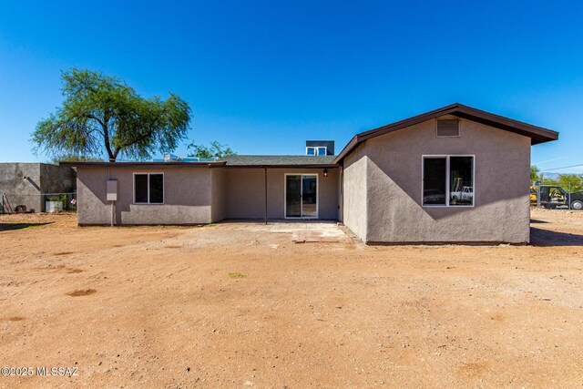back of property with stucco siding and fence