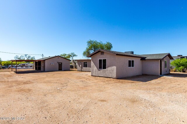rear view of property with stucco siding and a carport