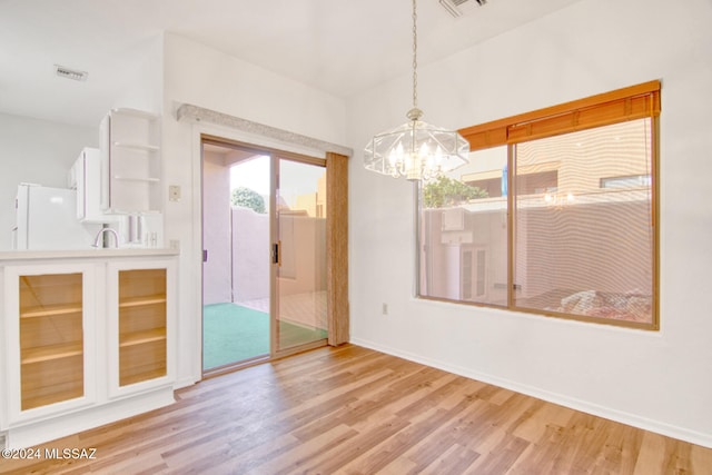 spare room with light wood-type flooring and a chandelier