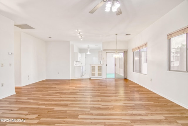 spare room with ceiling fan with notable chandelier and light hardwood / wood-style flooring