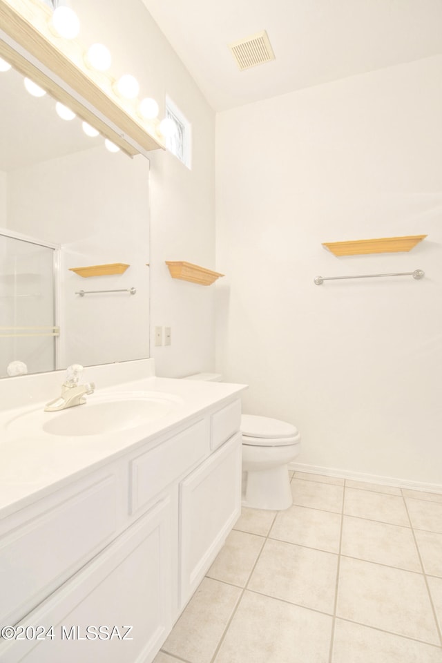 bathroom featuring tile patterned floors, toilet, vanity, and walk in shower