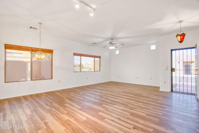 spare room with track lighting, light hardwood / wood-style floors, and ceiling fan with notable chandelier