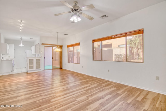 unfurnished room with ceiling fan with notable chandelier and light wood-type flooring