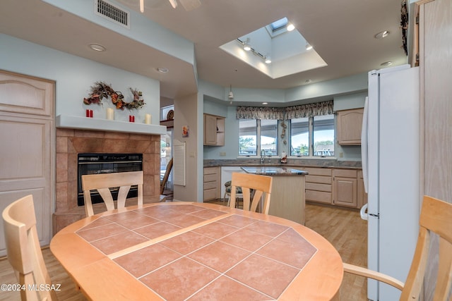 dining space featuring light wood-type flooring, a fireplace, and a skylight