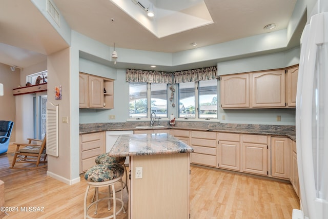 kitchen with light brown cabinetry, a center island, light hardwood / wood-style flooring, and sink