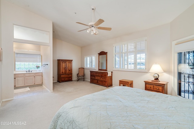 bedroom with ceiling fan, sink, ensuite bathroom, vaulted ceiling, and light carpet