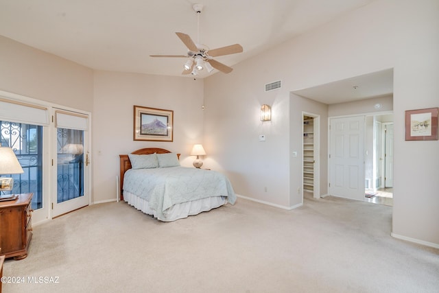 bedroom featuring a walk in closet, ceiling fan, access to exterior, light colored carpet, and a closet