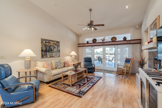 living room featuring ceiling fan, french doors, light hardwood / wood-style floors, and a brick fireplace