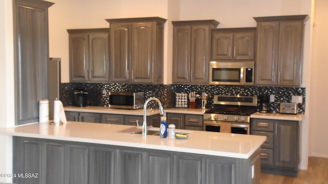 kitchen featuring stainless steel appliances, light countertops, a sink, and backsplash