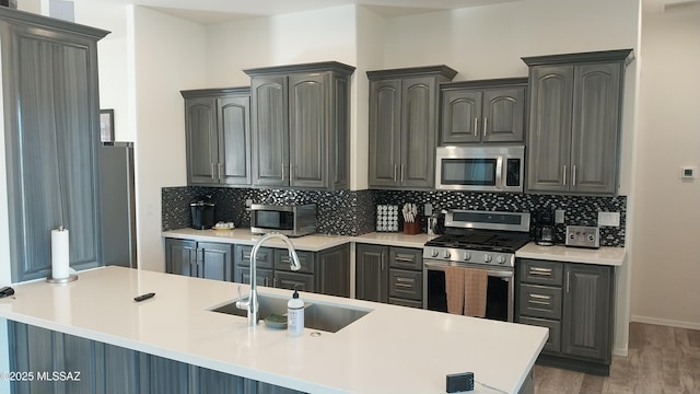 kitchen featuring stainless steel appliances, a sink, light countertops, and decorative backsplash
