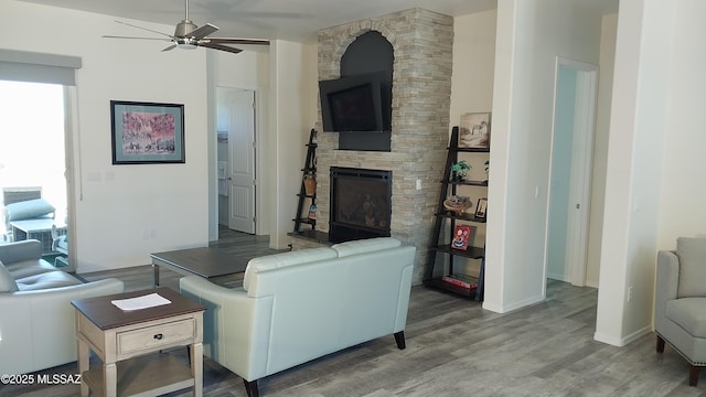 living room with a ceiling fan, a fireplace, and wood finished floors
