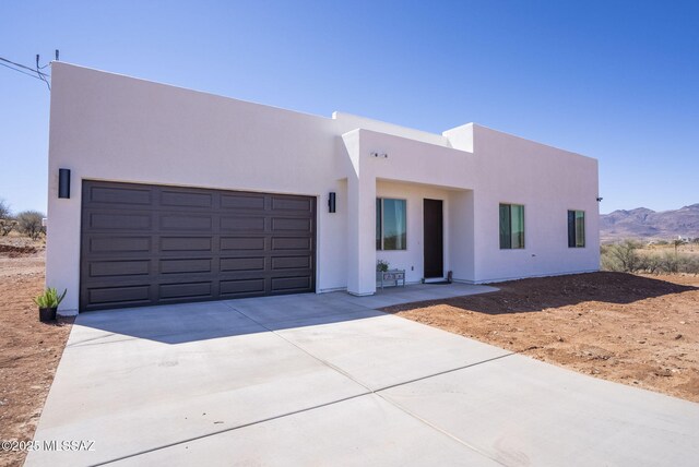 adobe home with a garage, a mountain view, and stucco siding