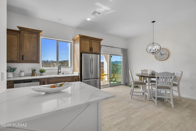 65A Avenida Pastor, Rio Rico, AZ 85648 - kitchen with stainless steel appliances, a sink, a chandelier, pendant lighting, and light stone countertops