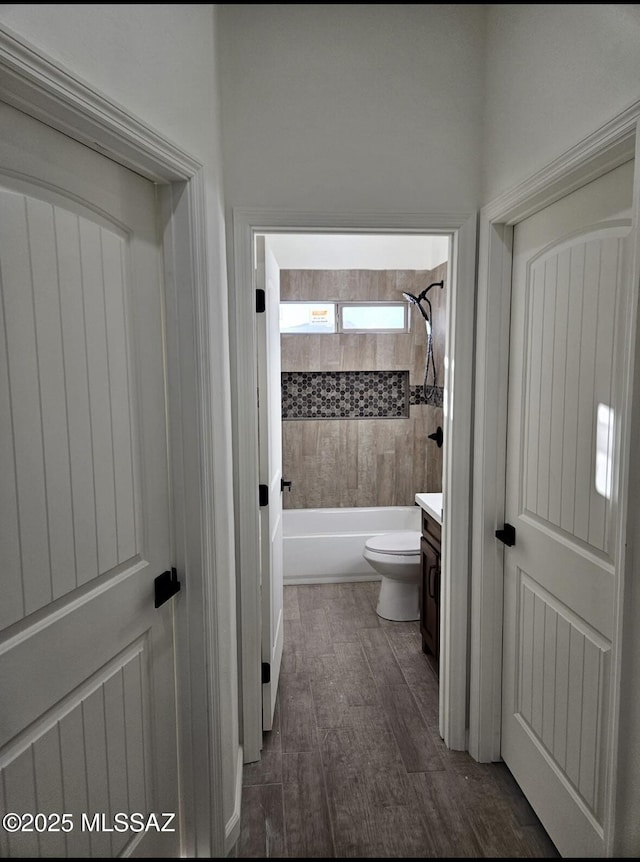 bathroom featuring shower / washtub combination, vanity, toilet, and wood finished floors