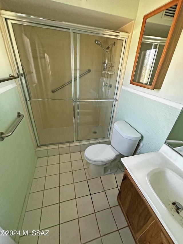 bathroom featuring tile patterned floors, vanity, a shower with shower door, and toilet