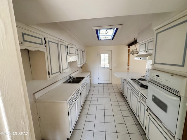 kitchen featuring white cabinetry, sink, vaulted ceiling, white appliances, and light tile patterned floors