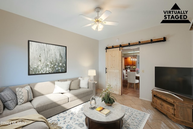 living room featuring ceiling fan, a barn door, and light tile patterned floors