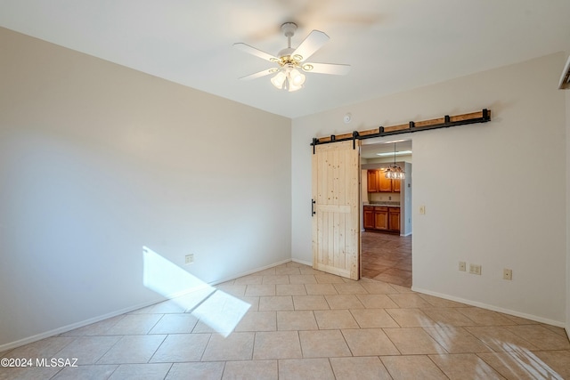 tiled spare room featuring ceiling fan and a barn door