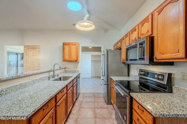 kitchen with sink, light stone countertops, appliances with stainless steel finishes, light tile patterned flooring, and kitchen peninsula