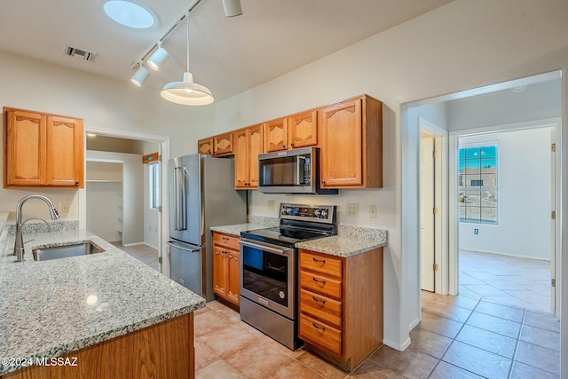 kitchen with light stone countertops, sink, rail lighting, and appliances with stainless steel finishes