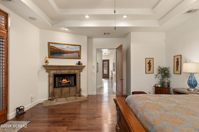 bedroom featuring a raised ceiling, a fireplace, and dark hardwood / wood-style floors