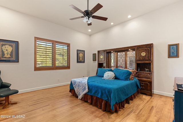 bedroom featuring ceiling fan, light wood-type flooring, and a high ceiling