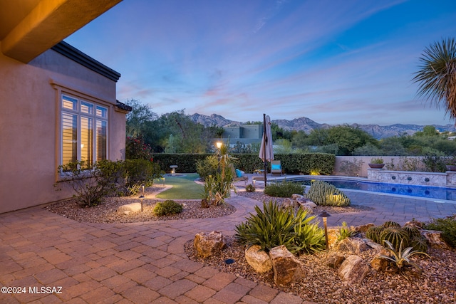 yard at dusk with a fenced in pool and a mountain view